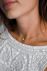 collier de mariage avec une chaine en or et une perle naturelle porté par une mariée pour le jour de son mariage